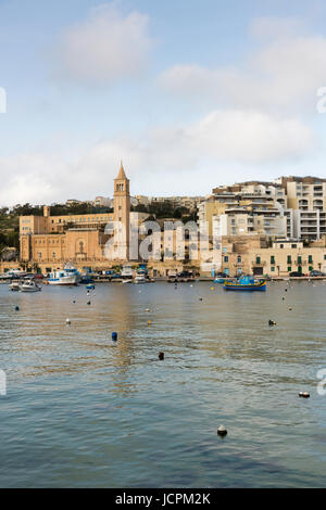 Edifici e appartamenti di vacanza e la chiesa parrocchiale dal porto di Marsaskala Malta Foto Stock