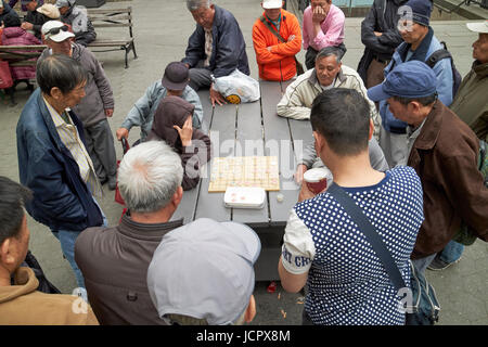 La folla a guardare due uomini xiangqi gioco di scacchi cinesi in Columbus Park chinatown New York City USA Foto Stock