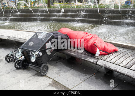 La persona senza dimora sleeping grezzo su una panchina nel parco vicino alla fontana al Columbus circle di New York City STATI UNITI D'AMERICA Foto Stock