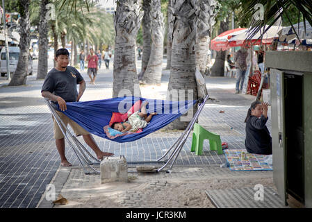 Paternità divertente. Padre che dondola il bambino in un'amaca mentre la madre emette gli ordini. Thailandia Sud-est asiatico Foto Stock