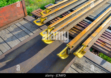 Elementi del fungo della rotaia. Trasporto di lungo rotaie di nuovo su di un carro merci. Percorso ad anello chiuso. Il gioco di guida. Carico speciale. Foto Stock