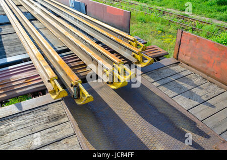 Elementi del fungo della rotaia. Trasporto di lungo rotaie di nuovo su di un carro merci. Percorso ad anello chiuso. Il gioco di guida. Carico speciale. Foto Stock