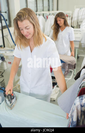 Lavoratori servizio lavanderia vestiti stirati a secco di ferro Foto Stock