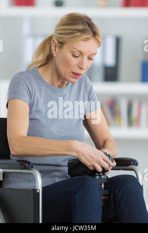 Medio-età donna su una sedia a rotelle in cerca immagine nella fotocamera Foto Stock