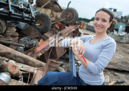 La donna lavora accanto a un metallo arrugginito pila di scarto Foto Stock