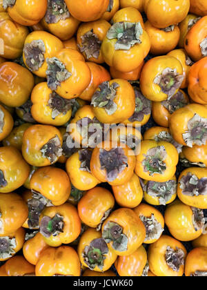 Persimmon organici frutti nella pila presso gli agricoltori locali mercato. persimmon sfondo. Foto Stock