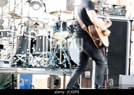 Musicista giocare la chitarra acustica sul drum set background. sfocatura dell'immagine. Foto Stock