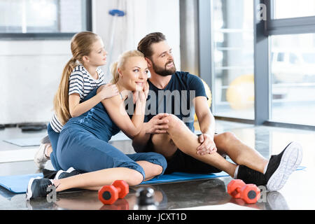 Ritratto di famiglia felice seduta sul tappetino in palestra Foto Stock