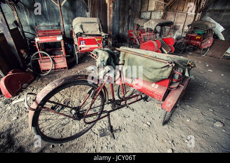 Cycle rickshaw cimitero in Indonesia. Questo è dove risciò ciclo vengono a morire o se sono fortunati avere riparato presso questo grintoso rickshaw garage Foto Stock