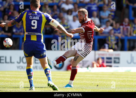 Il Wigan Warriors Sam Tomkins punteggi un drop goal pastWarrington lupi' Daryl Clark, durante la Ladbrokes Challenge Cup, quarti di finale di partita a Halliwell Jones Stadium, Warrington. Foto Stock