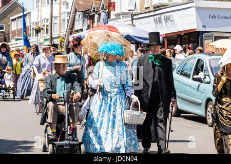 Broadstairs Dickens Week festival, la sfilata principale. Le persone vestite in costumi vittoriano come vari personaggi in Charles Dickens romanzi, camminando lungo la High Street in una giornata di sole. Foto Stock