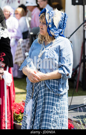 Senior donna vestito in costume Vittoriano, come Sarah Gamp, drunken Charles Dickens personaggio, tenendo in mano una bottiglia di Gin. Foto Stock