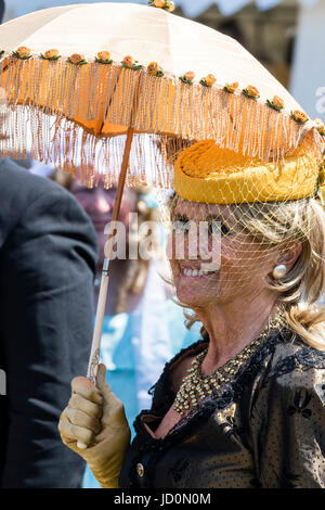 Ritratto, all'aperto, di alti donna, 60s, vestito in costume Vittoriano. Azienda parasol, indossa il cappello con velo, sorridente. Foto Stock