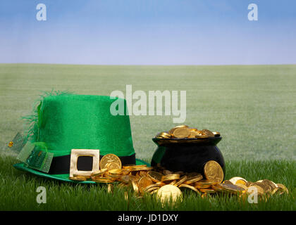 Pentola d'oro debordi sul verde erba, Leprechaun hat posa accanto ad essa, erba verde campo al di fuori all'orizzonte. Spazio di copia Foto Stock