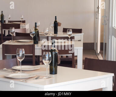 Set di tabelle per il pranzo o la cena. Le bottiglie di vino sono presenti. Foto Stock
