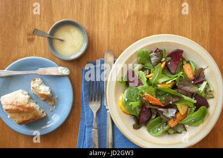 Vista aerea di un arrosto di barbabietola e carota insalata servita con pane e burro su una superficie in legno Foto Stock