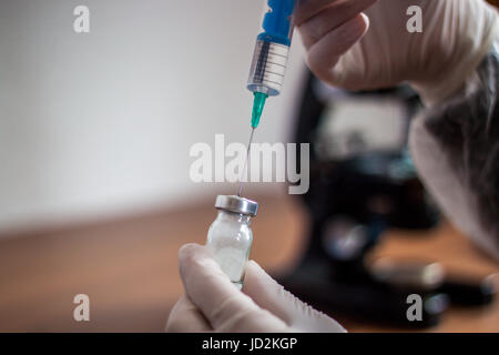 Giovane medico prepara una iniezione ad un paziente, il liquido iniettato nell'ago, tenendo molto attentamente Foto Stock