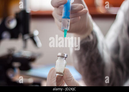 Giovane medico prepara una iniezione ad un paziente, il liquido iniettato nell'ago, tenendo molto attentamente Foto Stock