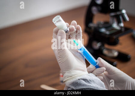 Giovane medico prepara una iniezione ad un paziente, il liquido iniettato nell'ago, tenendo molto attentamente Foto Stock