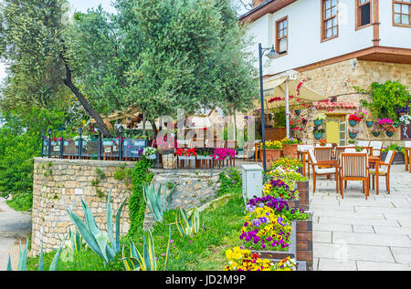 L'outdoor cafe in Kaleici decorate con pancies e nelle petunie in vasi, molti tavoli situato all'ombra albero di olivo, Antalya, Turchia. Foto Stock