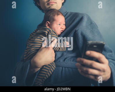 Un giovane padre in un accappatoio sta prendendo un selfie con suo Figlio bambino Foto Stock