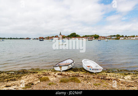 Coppia di imbarcazioni a remi sulla riva e vista panoramica di Bosham, una costa sud villaggio costiero situato nel porto di Chichester, West Sussex, in Inghilterra meridionale, Regno Unito Foto Stock