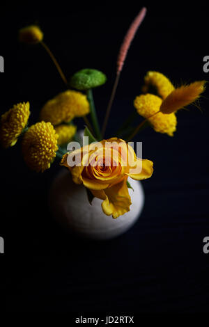 Un piccolo addobbo floreale su sfondo nero.Verde e schema colore di giallo. Crisantemo, rose, grani Foto Stock