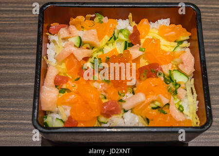 Riso Chirashi il cibo giapponese nel recipiente quadrato sul tavolo di legno vicino fino Foto Stock