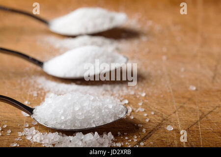 Chiusura del cucchiaio riempito con sale su sfondo di legno Foto Stock