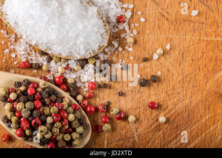 Cucchiai di legno con sale marino e pepe su sfondo di legno con spazio di copia Foto Stock