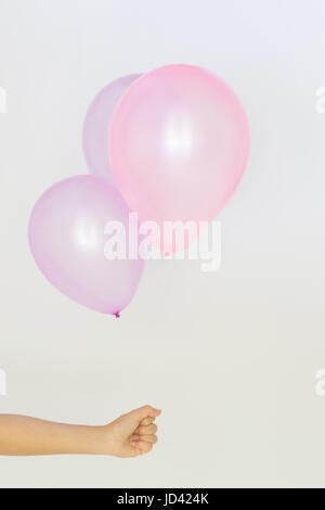 Womans mano trattiene palloncini in uno sfondo bianco Foto Stock