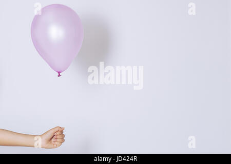 Womans mano trattiene palloncini in uno sfondo bianco Foto Stock