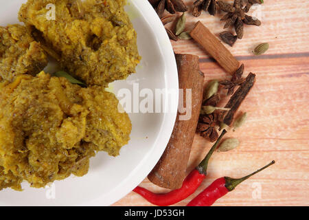 Piatto malese Rendang Ayam o a secco di pollo al curry e Ketupat Nasi (gnocco di riso) su sfondo di legno Foto Stock