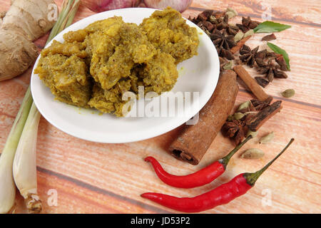 Piatto malese Rendang Ayam o a secco di pollo al curry e Ketupat Nasi (gnocco di riso) su sfondo di legno Foto Stock