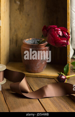 Ancora vita con singolo peonia fiore nel vecchio e rustico vaso. Foto Stock