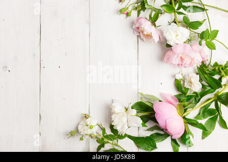 Fiori rosa e bianchi su un tavolo di legno. Ghirlanda fatta con le peonie e rose selvatiche. Elevato La chiave, Copia dello spazio. Foto Stock