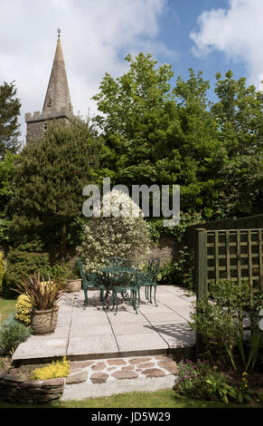 Ghisa mobili da giardino. Un tavolo e sedie dipinte di verde scuro. In un paese di lingua inglese il giardino. Devon, Inghilterra, Regno Unito Foto Stock