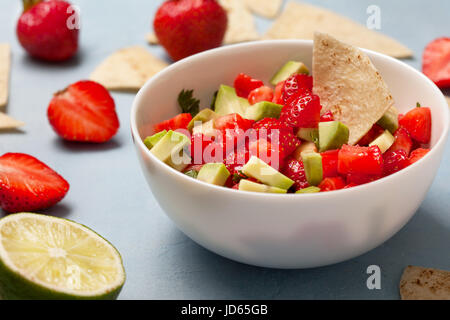 Salsa di fragole avocado in una terrina di fragole fresche su sfondo blu Foto Stock