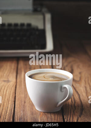 Tazza di caffè e la vecchia macchina da scrivere sul vecchio sfondo di legno. Concetto. Dark. Foto Stock