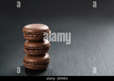 Il cioccolato macarons impilati sulla scheda di ardesia Foto Stock