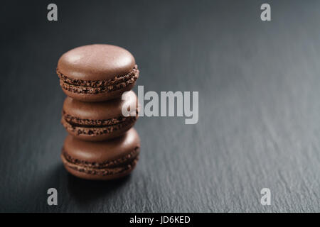 Il cioccolato macarons impilati sulla scheda di ardesia Foto Stock