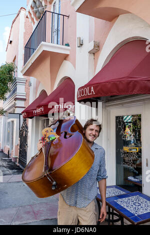 Miami Beach Florida, Espanola Way, adulti uomo uomo uomini maschio, musicista, a piedi, trasporto contrabbasso, strumento musicale, visitatori viaggio viaggio tou tour Foto Stock