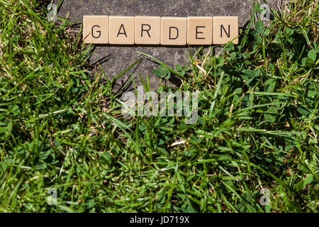 Piastrelle scrabble sdraiati sull'erba nel giardino che mostra la parola giardino Foto Stock