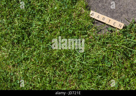 Piastrelle scrabble sdraiati sull'erba nel giardino che mostra la parola Garten Foto Stock