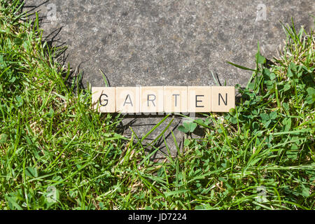 Piastrelle scrabble sdraiati sull'erba nel giardino che mostra la parola Garten Foto Stock