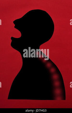 Concetto di malattia umana e dolore localizzazione su silhouette - abstract uomo africano con dolore acuto nella colonna vertebrale, a bocca aperta, isolato su sfondo rosso, vista dall'alto, piatto laici. Foto Stock
