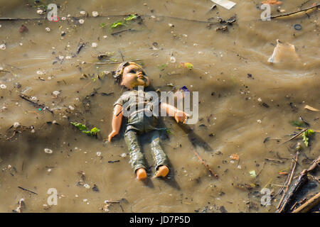 Un bambino la bambola forlornly flottante nel fiume Thames, London, Regno Unito Foto Stock