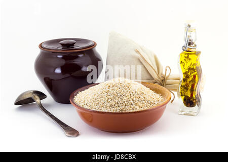 Ancora la vita di orzo cereale in ceramica, pial ceramica pentola, vecchio cucchiaio e borsa di tela per i cereali, olio con spezie e condimenti, isolato sul retro bianco Foto Stock