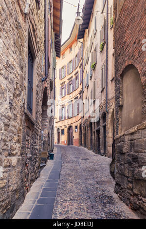 Vecchio strette strade di pietra di Bergamo Alta, circondato da case e le antiche mura, Italia Foto Stock