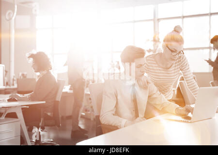 Giovane imprenditrice aiutando il suo collega per risolvere il problema del lavoro Foto Stock